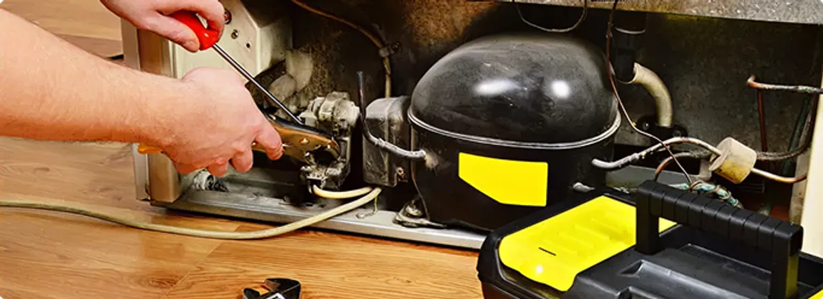 Refrigerator repair technician fixing the compressor and wiring in Pacific, WA
